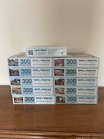 Side stack view showing nine puzzle boxes with 300-piece marking