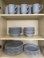 Full set on three cabinet shelves showing mugs, plates, bowls