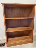 Front view of maple bookshelf showing three shelves and overall structure