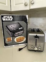 Front of Star Wars waffle maker box beside stainless steel toaster