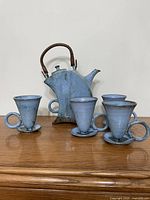 Group view: teapot with rattan handle and four matching blue-glazed mugs