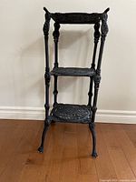Full front view of three-tier black cast iron plant stand