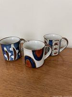 Front view of three stoneware mugs showing different designs