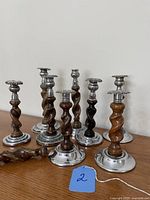 Group view of eight barley twist candlesticks and spare wood spindle