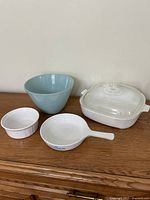 Group shot of all four items: blue mixing bowl, white casserole with lid, white skillet, white ramekin