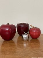 Group shot of four apple figurines on wooden surface