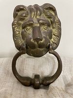 Front view of brass lion head door knocker with ring pull