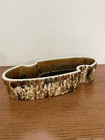 Angled side view of oval ceramic Ikebana bowl showing exterior drip glaze and shape