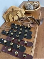 Group shot of wood nativity, sleigh bell hangers, metal horns, wood bowl with three bark ornaments on wood surface