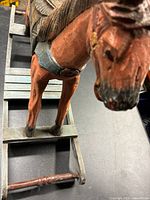 Photo of the front and side view of the hand-carved wooden rocking horse showing detailed face, real horse hair mane, and painted saddle.
