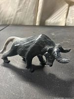 Front side view of the dark gray/black marble bull figurine showing the detailed horns and body carving.