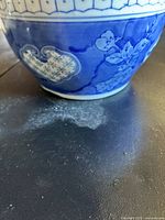 Close-up photo of the bottom edge and some floral painted details of the blue and white porcelain bowl