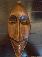 Full view of the vintage cast plaster face mask showing the entire elongated face with closed eyes and smiling mouth.