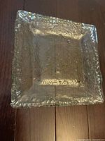 Top view showing the textured surface, square shape and ruffled edges of the glass dish.