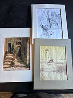 Three loose matted art pieces shown together on a black background: pencil sketch, lighthouse print, and Mediterranean stairway print