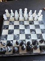 Full view of marble chessboard set up for play with all chess pieces in position