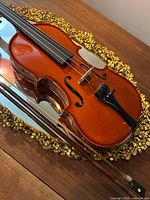 Angle view of the Massanet violin with bow on decorative mirror.