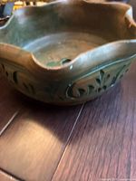 Side view of medium green ceramic planter showing scalloped edges and floral carved pattern on the side.