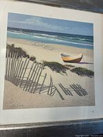 Framed giclée print showing a beach scene with canoe, fence shadows, and ocean waves.