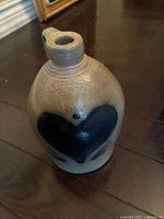 Full view of the stoneware jug showing blue heart motif on beige body and single handle with short wide spout.