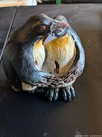 Close-up of two penguins embracing, showing detailed paint and texture.