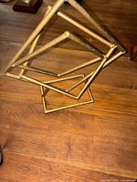 Top angled view of gold-tone metal geometric sculpture showing twisted square frame design on wooden surface.