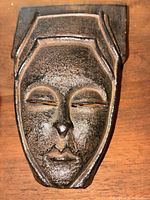 Close-up front view of vintage deity mask showing textured features and geometric frame.