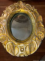 Front view of the vintage hand-carved wooden mirror with floral design and gold gilding.