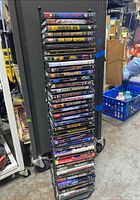 Photo of entire DVD lot stacked vertically in black metal DVD stand showing titles and lot size.