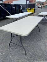Perspective photo showing the full length and metal legs of the folding table in an outdoor setting.