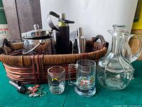 Full view of contents in the rectangular wicker basket including bar accessories, glassware and ice bucket