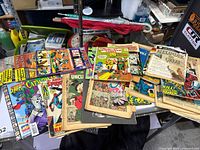 Photo showing a spread of assorted vintage comic books including Batman, Spider-Man, Catwoman, and Uncle Scrooge; some with damaged or missing covers