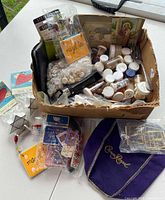 Box filled with small containers primarily of buttons, some vintage photographs and small miscellaneous items