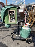 Full view of Mosquito Magnet machine on wheeled stand with green tank and some wrapped parts.