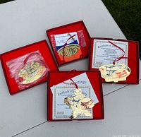 Four NASCAR collectible gold-toned Christmas ornaments with certificates of authenticity in red presentation boxes.