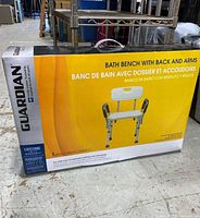 Box showing front image and Guardian branding, indicating it is a bath bench with back and arms, new in box.