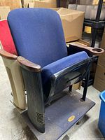 Full view of the original Radio City Music Hall theatre seat with blue fabric upholstery, wooden armrests, and metal base.