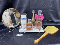 Group shot of perfume bottles on white tray with round gold-framed mirror and yellow handheld mirror