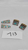 Two pairs of clip-on earrings on a white surface with a card labeled 713, showing rectangular turquoise silver earrings and decorated turquoise silver earrings