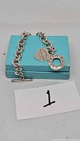 Chain bracelet with heart and circular tags displayed on Tiffany blue box