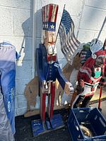 Front and side view of the 4ft tall Uncle Sam wooden folk art statue showing painted details, American flag, and wear on paint.