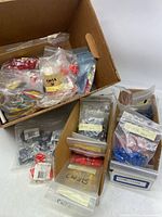 Box containing many small resealable plastic bags with assorted new electronic plugs, clips, and posts from Velleman.