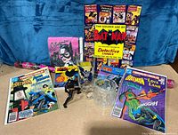 Full lot view showing comic books, figurines, books, gift wrap, and glassware