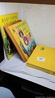 Four vintage children's books standing and lying on a white surface, showing colorful illustrated covers and titles including Just Danny Kids, Baby Land, and Baby Farm Animals.