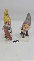Front view of two vintage Goebel Co-Boy gnome figurines, one with yellow hat and blue jacket, other with gray hat and green jacket