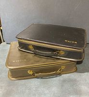 Two closed briefcases stacked, black for WAIS-R and brown for WISC-R, showing exterior wear.