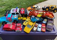 Overview of all toy cars grouped on a purple tray on grass showing variety in types and colors.
