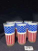 Six glass tumblers decorated with USA flag design against a black background.