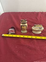 Three antique lighters side by side with tape measure for scale