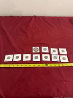 All eleven Jefferson nickels in cardboard flips lined up beside measuring tape